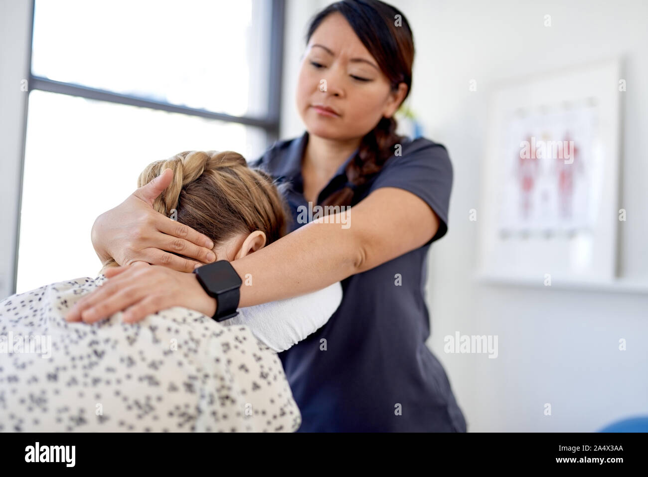 Chinese woman massage therapist giving a neck and back pressure Stock