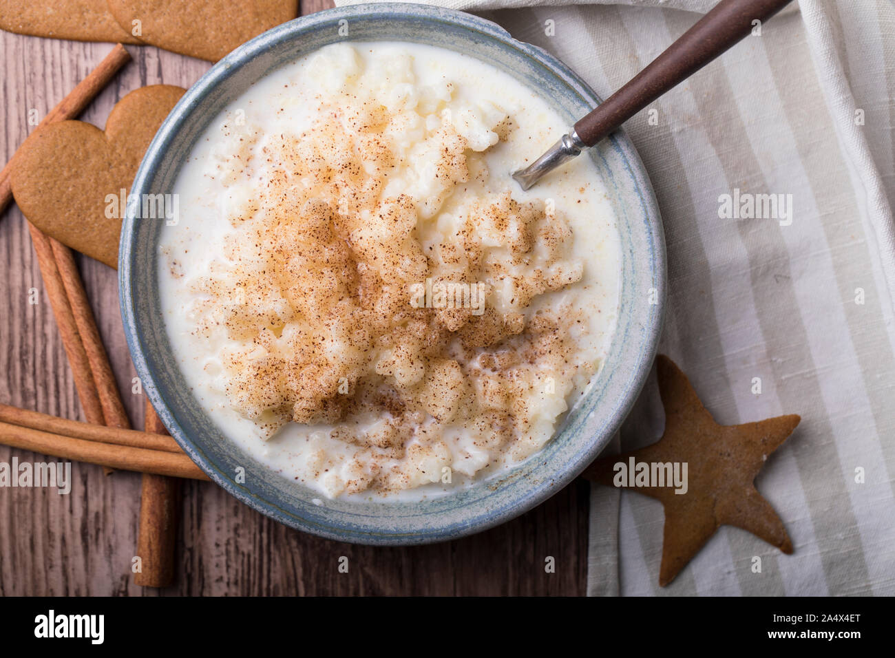 Traditional rice pudding also known as tomtegröt or swedish risgrynsgröt. The rice pudding is in a blue ceramic bowl on a wooden table, seen from abov Stock Photo