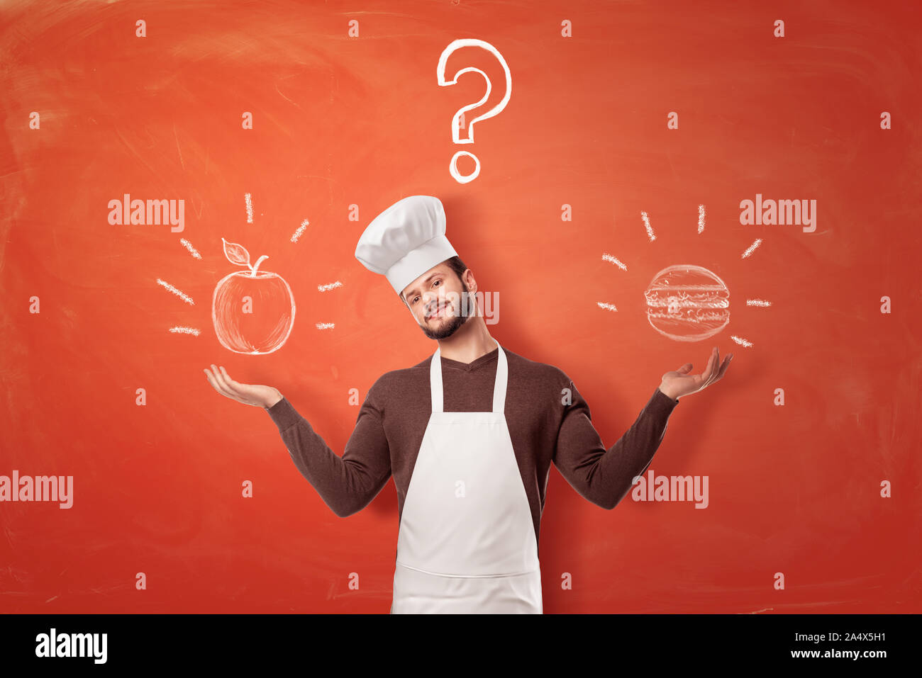 A young bearded chief makes a scale shape with his arms with an apple and a burger on each side from him. Stock Photo