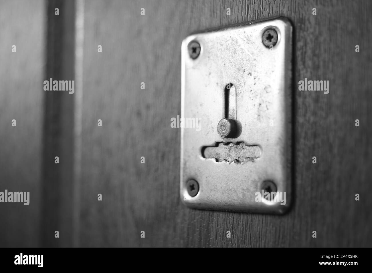 Wooden door with chrome keyhole and sunlight, black and white photo. Stock Photo