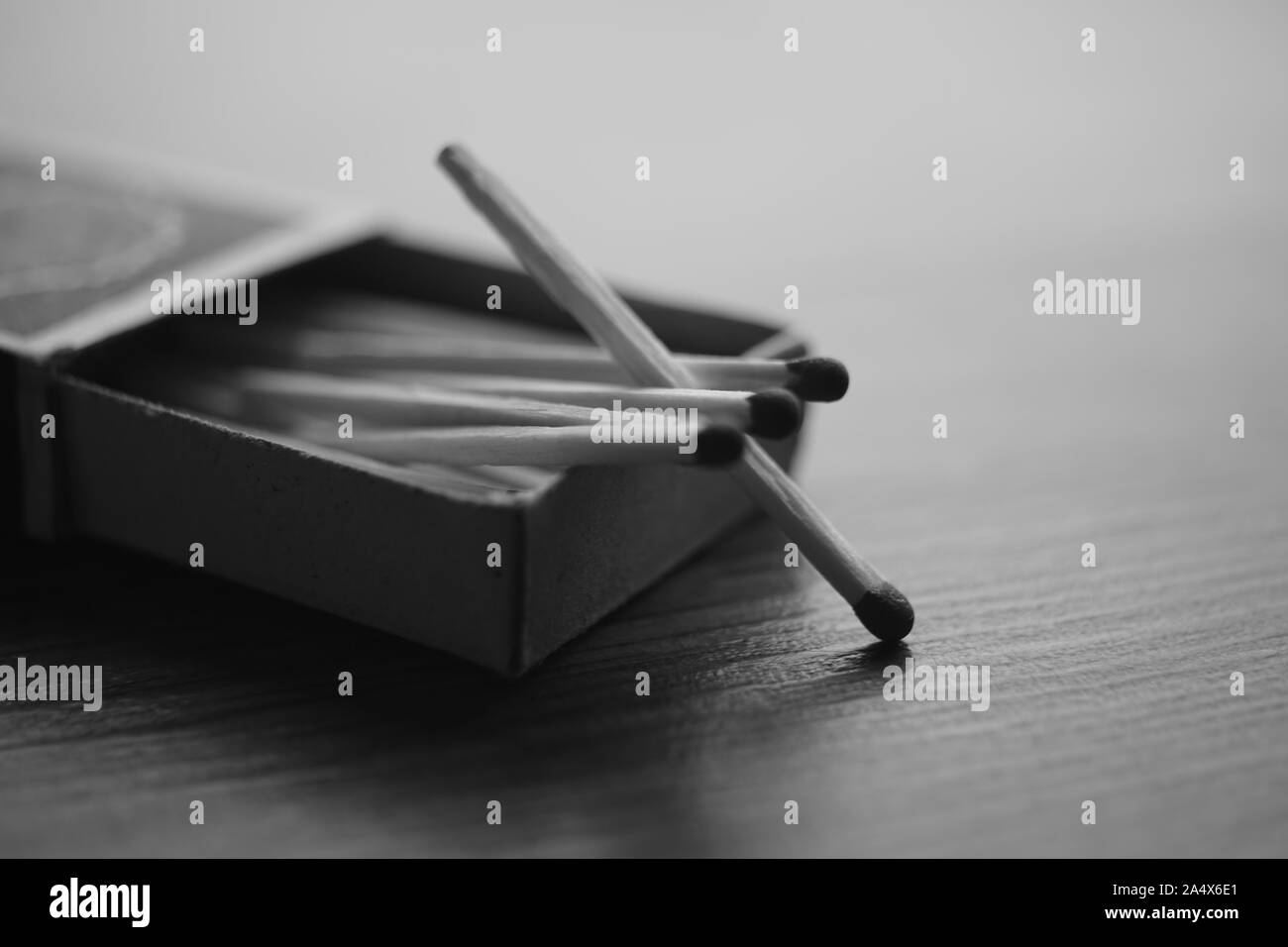 Open cardboard box with matches on the wooden table, copy space. BW photo. Stock Photo