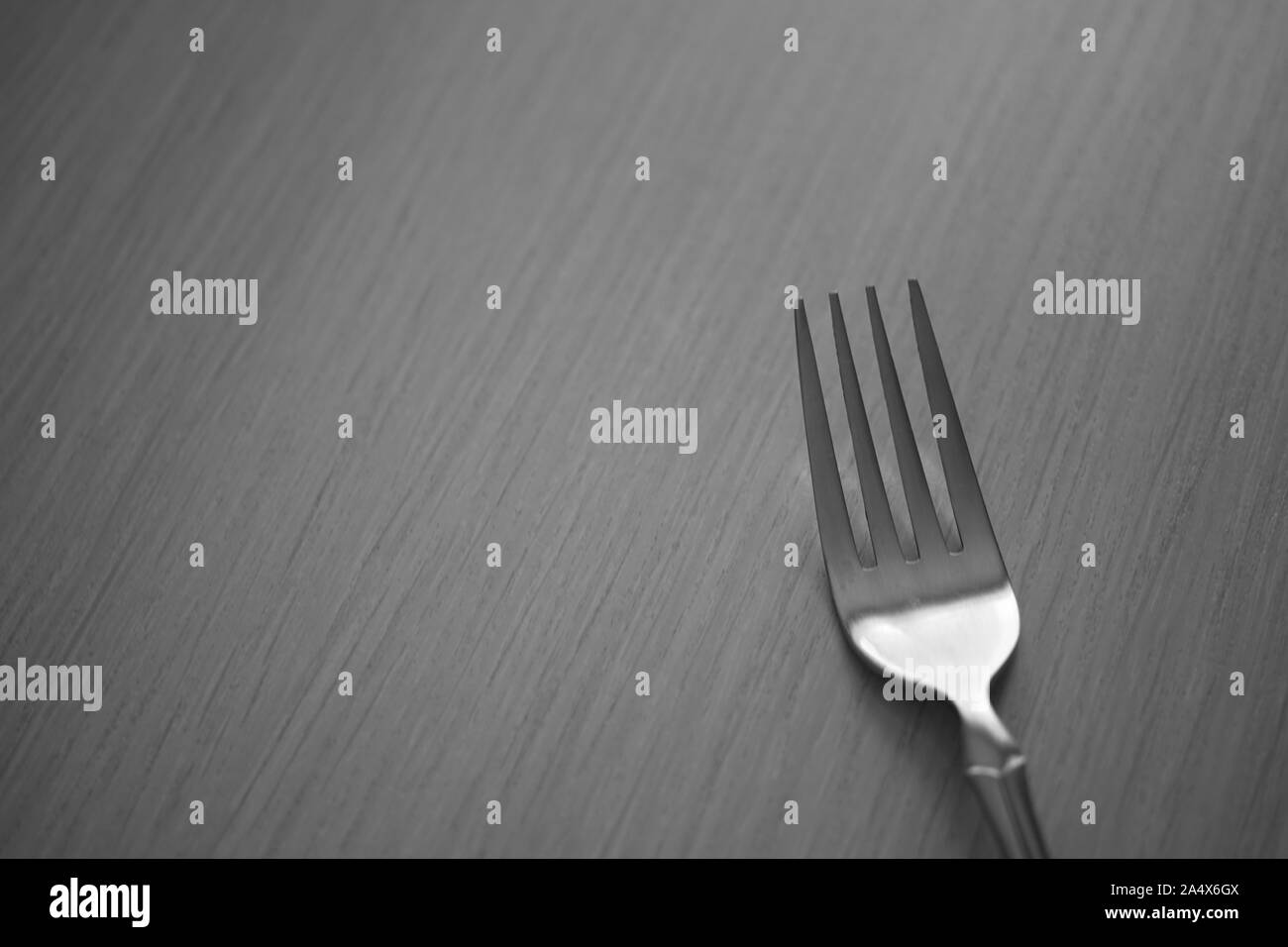 Fork on the wooden table. Black and white photo. Top view. Stock Photo