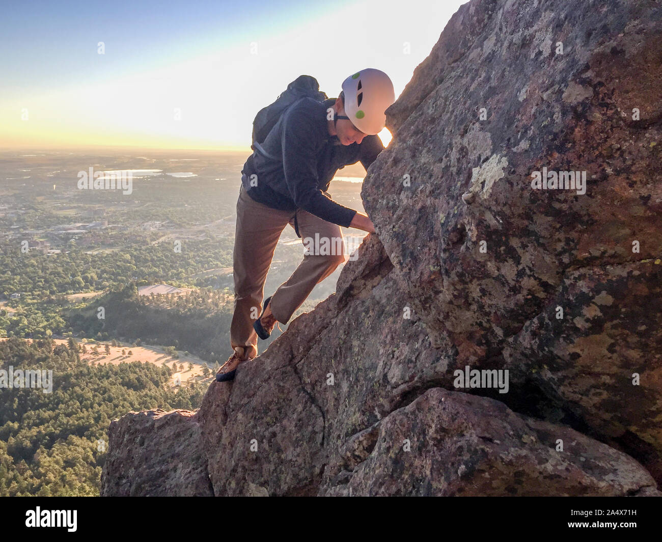 Man climbs freesolo on steep ridge shortly after sunrise Stock Photo