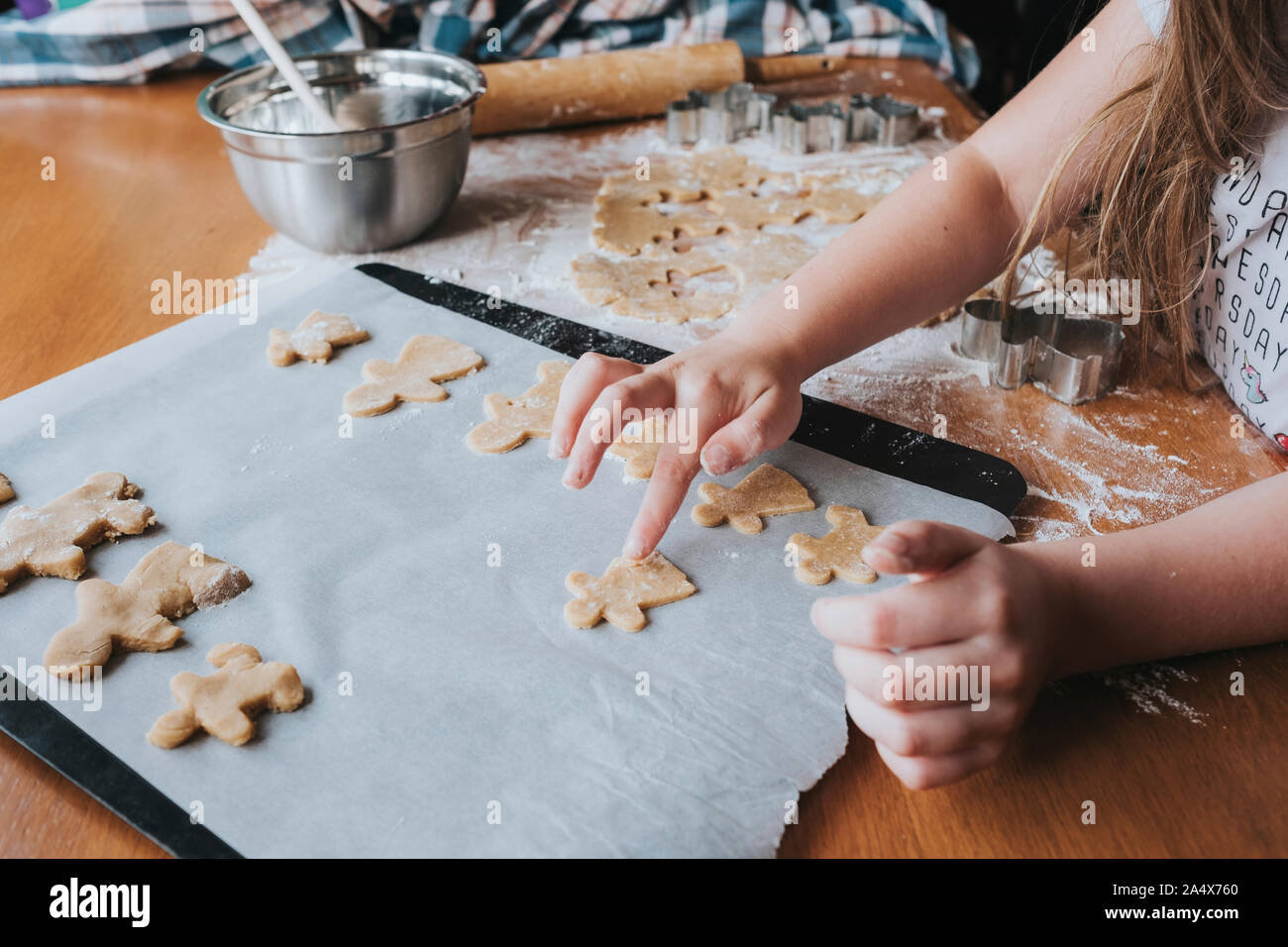 Young girl putting gingerbread man on baking tray Stock Photo