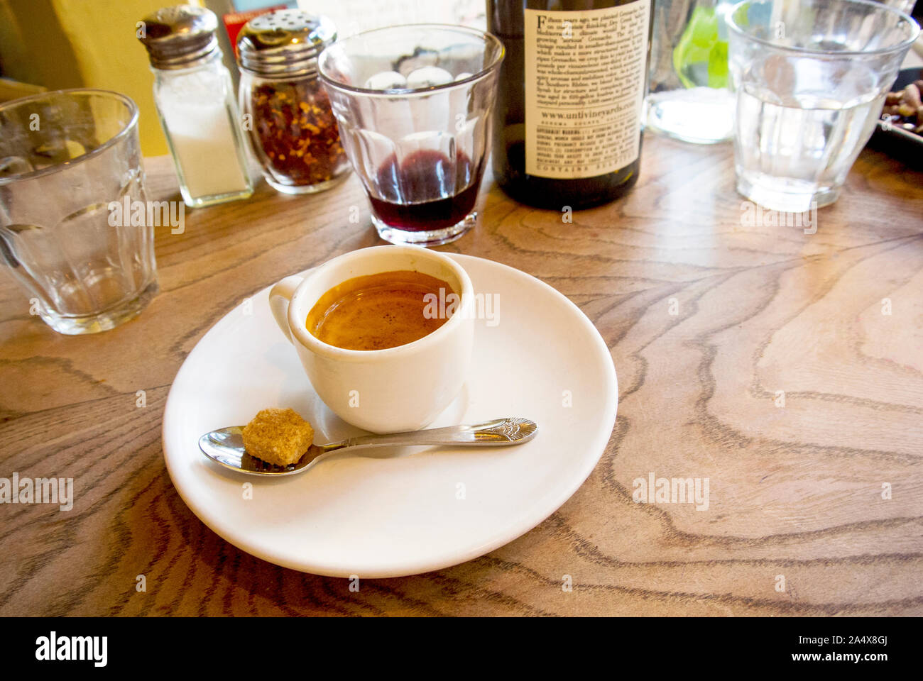A shot of espresso sits on a table after a meal enjoyed with wine. Stock Photo