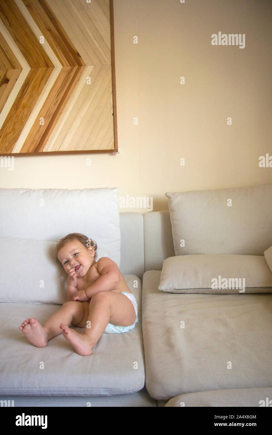 A smiling baby rolls around on a couch Stock Photo Alamy