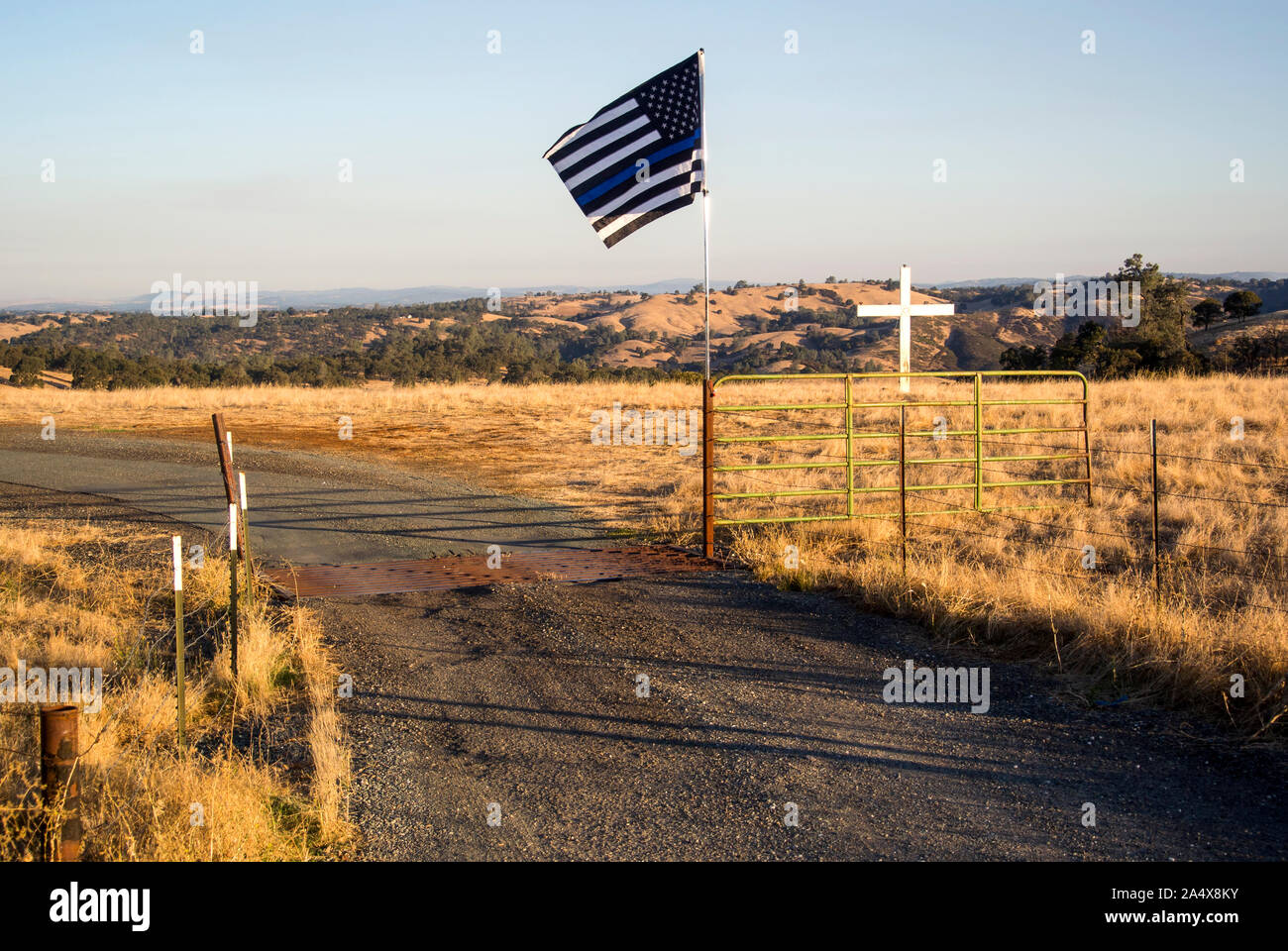 A blue striped law enforcement flag stands in front of a white cross. Stock Photo