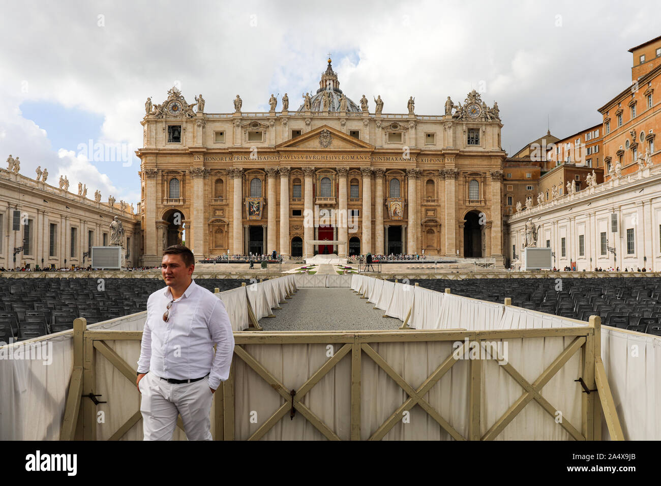 Male tourist posing for camera at St. Peter's Square with St. Peter's Basilica in the background in Vatican City State Stock Photo