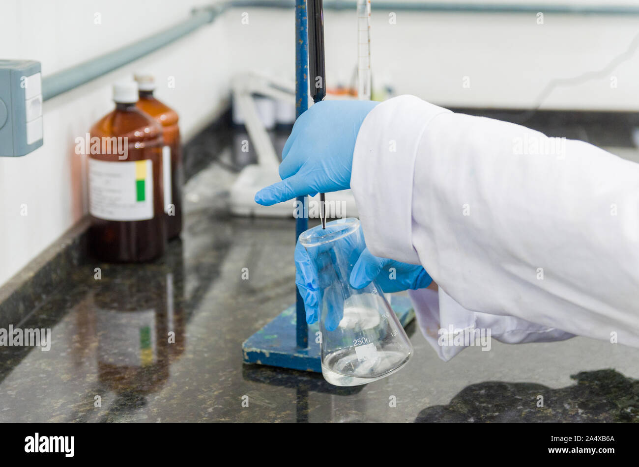 Woman hands performing titration test on chemical quality control Stock