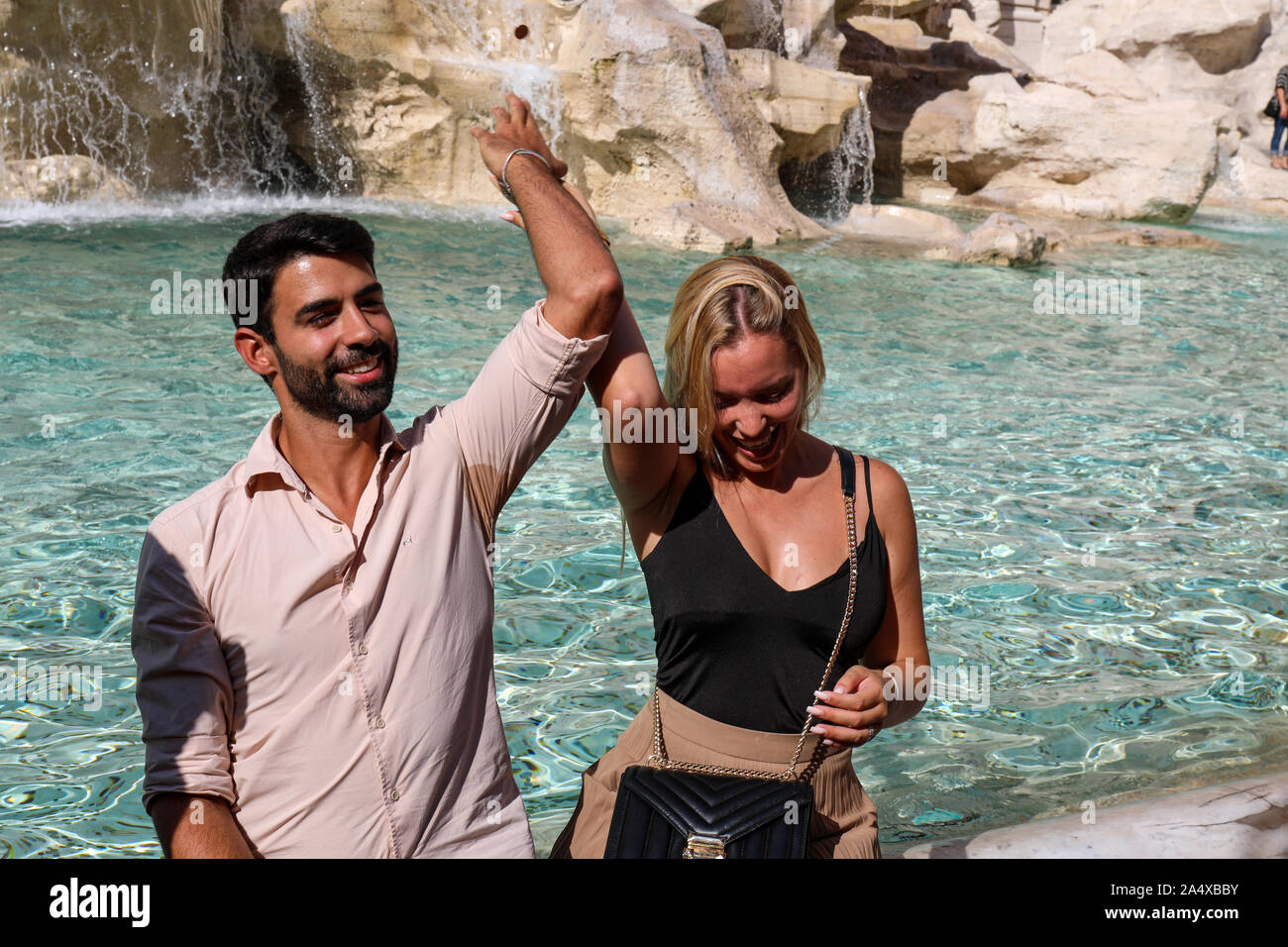 Couple throwing a coin over the shoulder into the Trevi Fountain in Rome, Italy Stock Photo