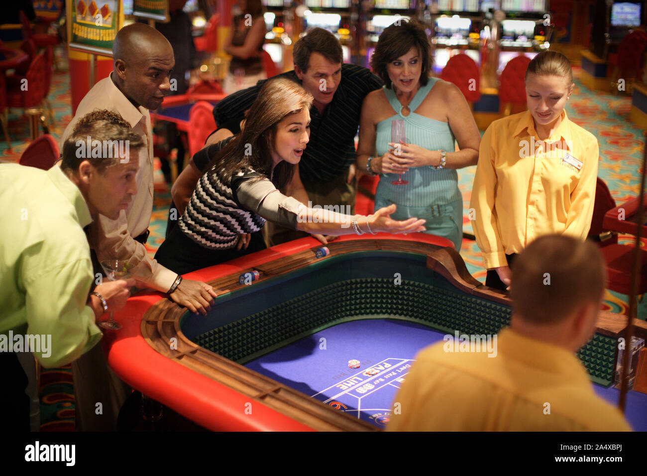 Group of adults at a casino watching in anticipation as a bet is being made by another patron. Stock Photo