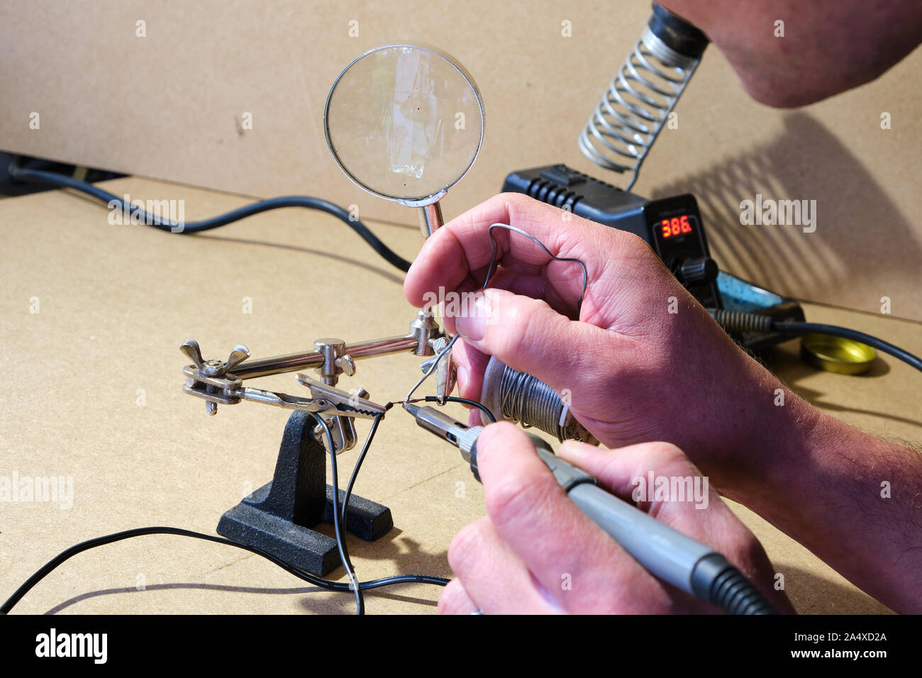 Close up of a man soldering wiring using a soldering station soldering iron and helping hands clips in a DIY environment Stock Photo
