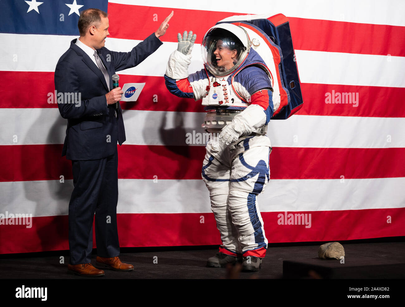 NASA Administrator Jim Bridenstine, left, high fives Kristine Davis, a spacesuit engineer at NASA's Johnson Space Center, wearing a ground prototype of NASA's new Exploration Extravehicular Mobility Unit (xEMU), during a demonstration of the suit, on October 15, 2019, at NASA Headquarters in Washington. The xEMU suit improves on the suits previous worn on the Moon during the Apollo era and those currently in use for spacewalks outside the International Space Station and will be worn by first woman and next man as they explore the Moon as part of the agency's Artemis program. NASA Photo by Joe Stock Photo