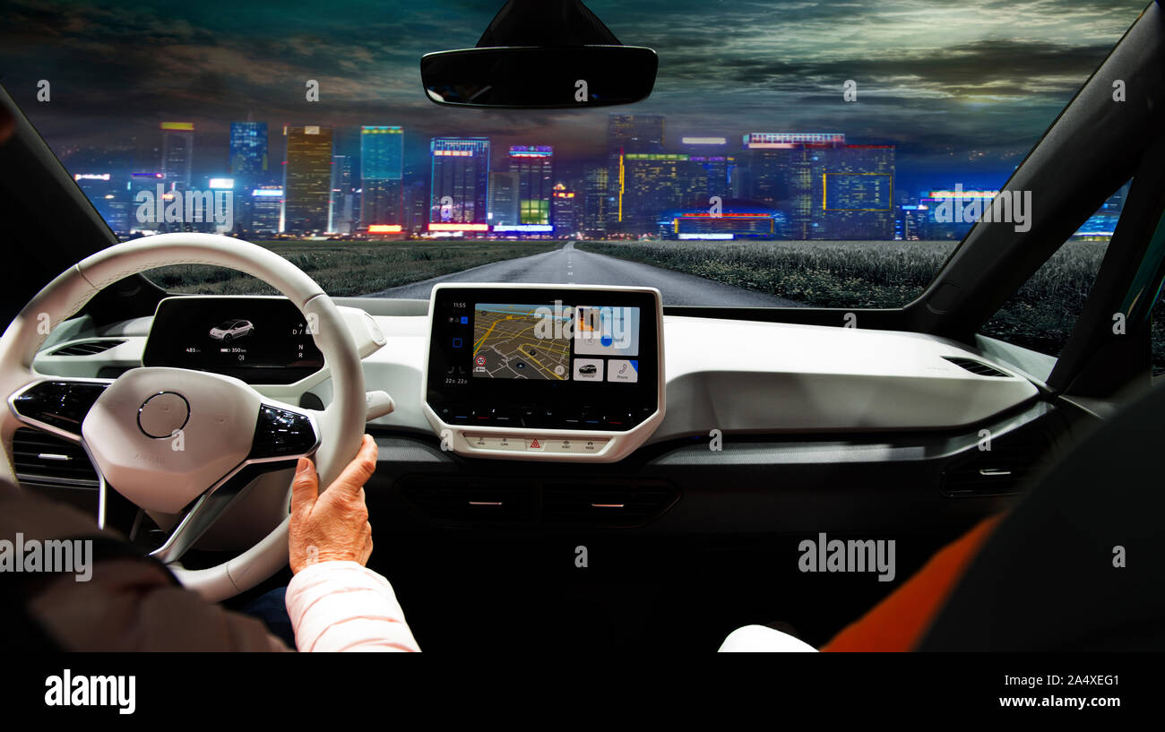 Two women driving a super modern car on an asphalt highway towards a night city. Stock Photo