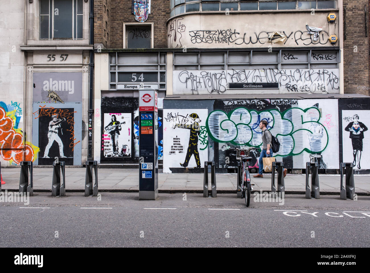 People walking in Great Marlborough Street, Soho in front of walls covered in graffiti murals and street art Stock Photo