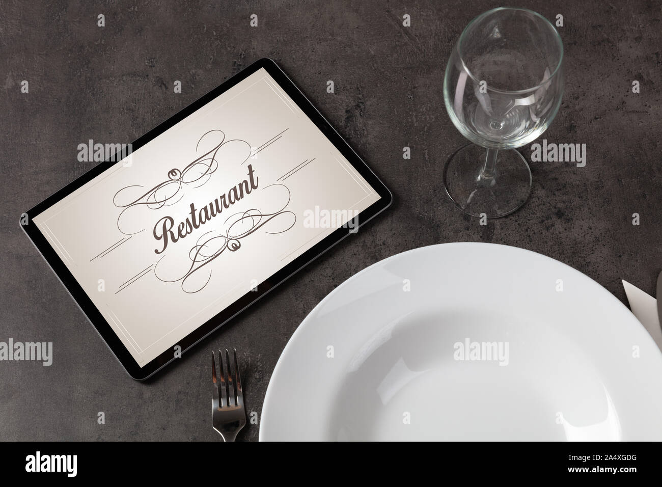 Tablet with stylish restaurant logo and laid table Stock Photo