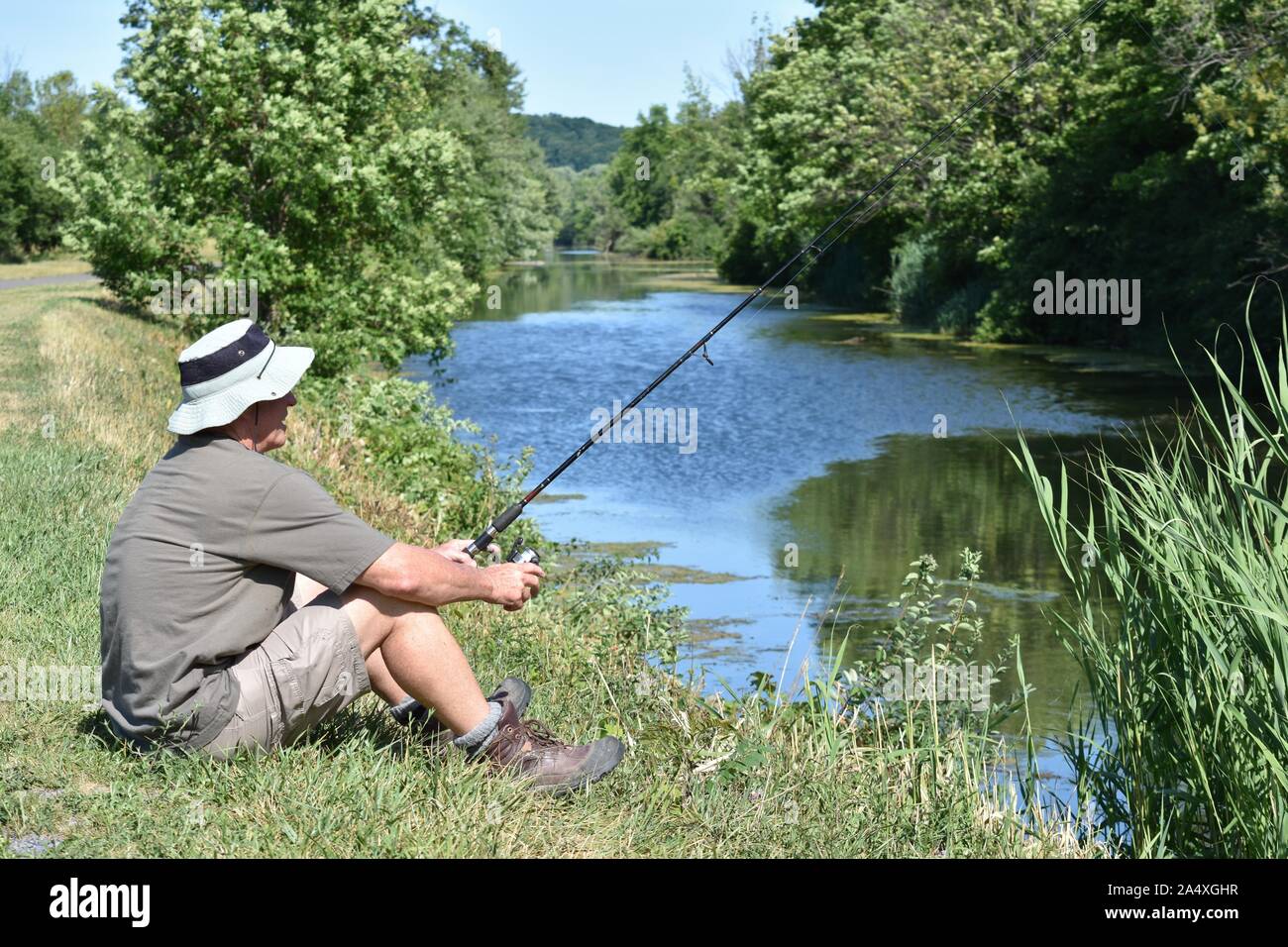 Male Fisherman Resting With Fishing Rod Outdoors Stock Photo