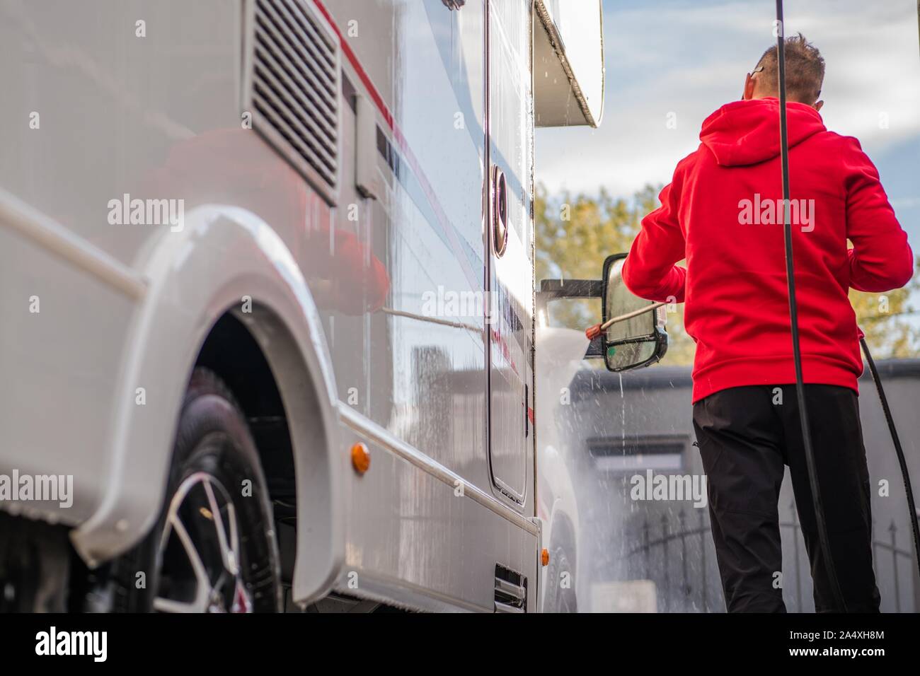 Men Cleaning His Camper Van Motorhome in a Car Wash Using Pressure