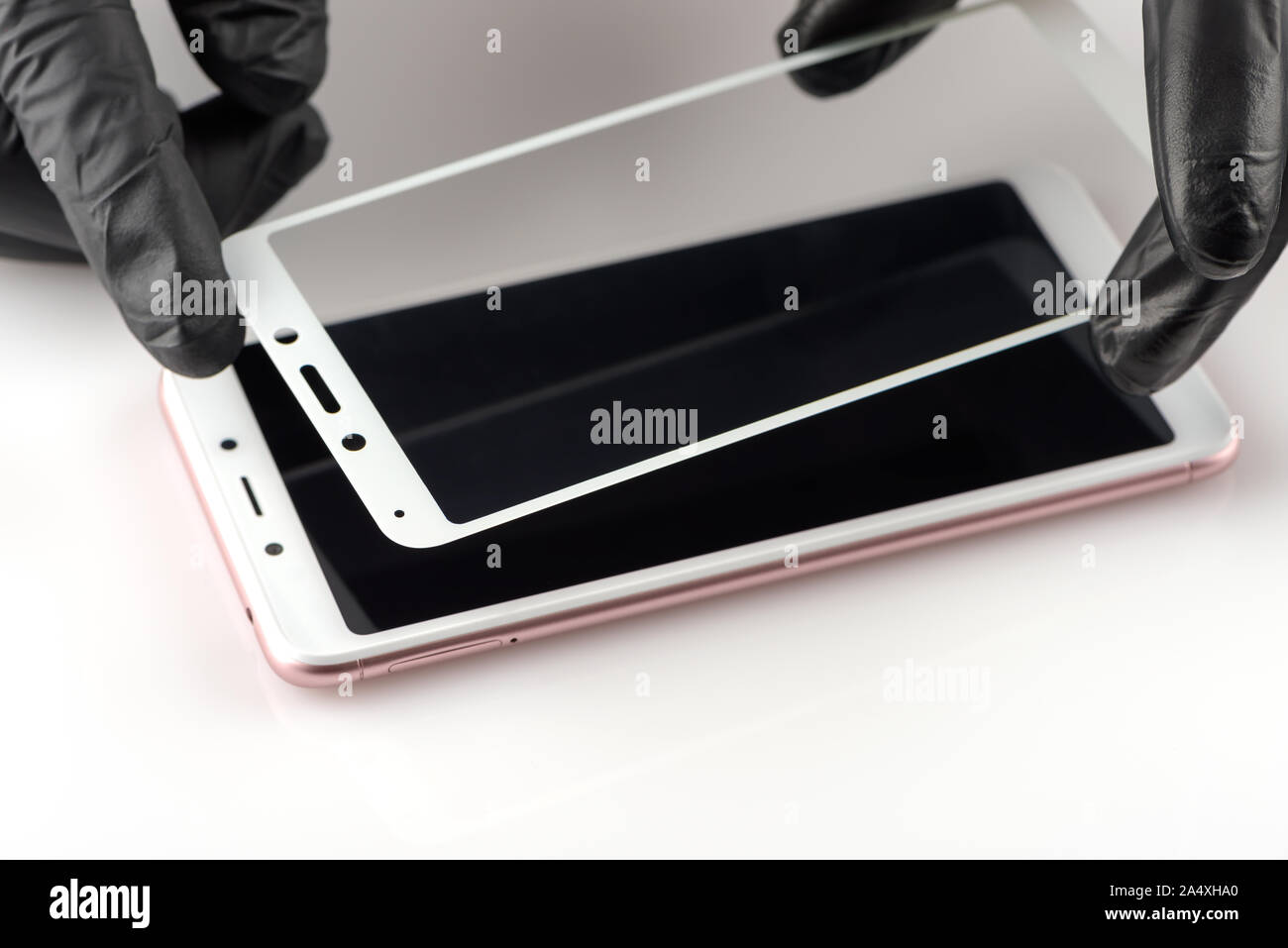 A man is installing a protective glass on the screen of a smartphone. Stock Photo