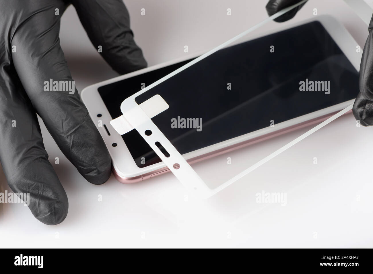 A man is installing a protective glass on the screen of a smartphone. Stock Photo