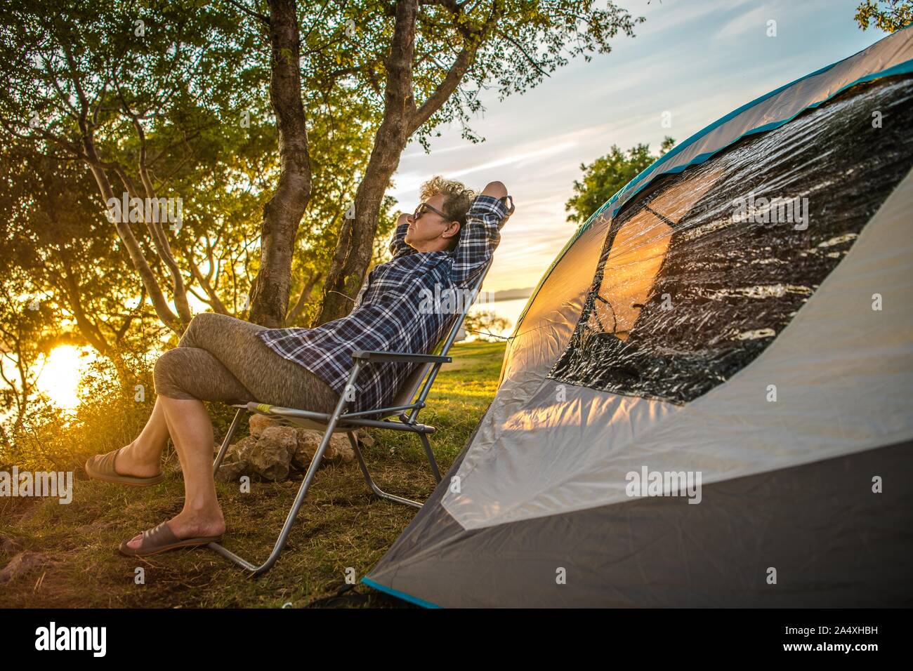 Retirement Summer Trip with a Tent. Caucasian Woman in Her 60s in Front of Her Tent Enjoying Her Free Time. Stock Photo