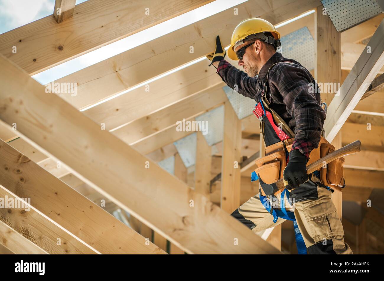 Construction Worker on Duty. Caucasian Contractor and the Wooden House Frame. Industrial Theme. Stock Photo