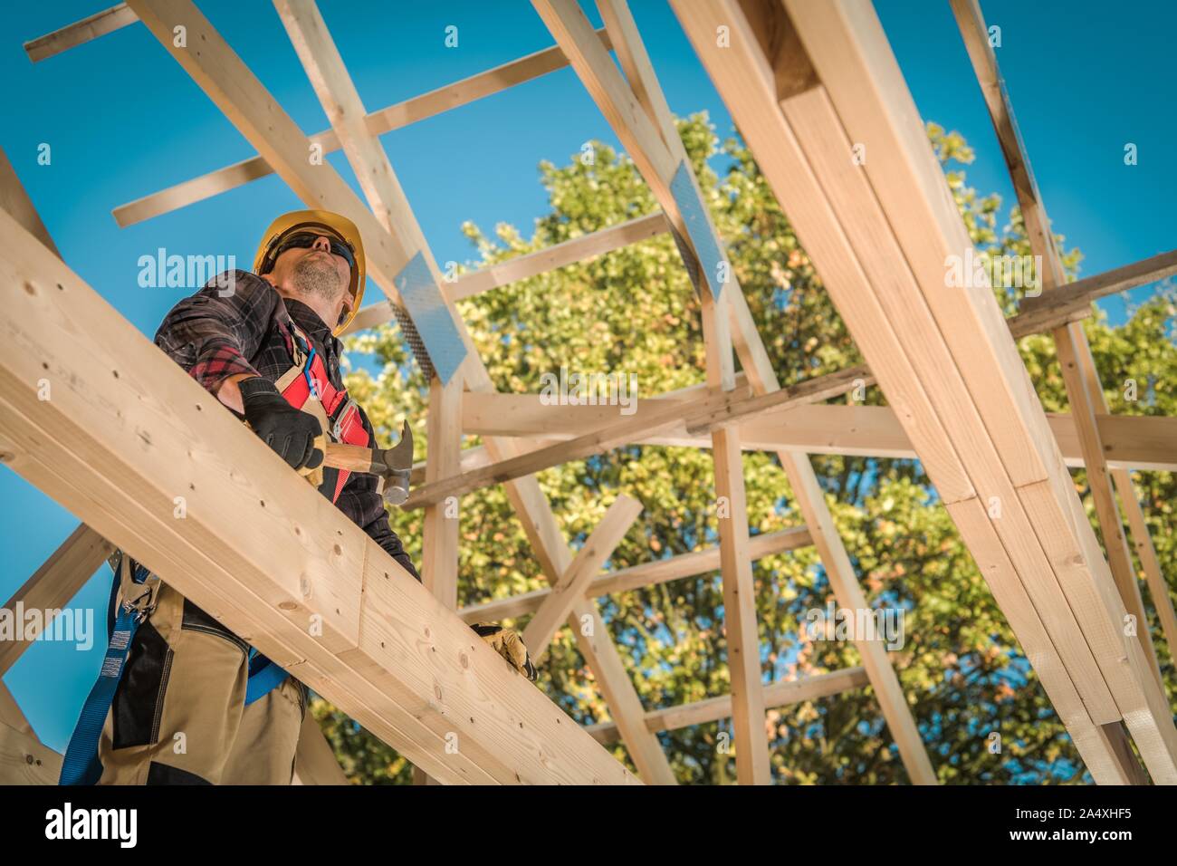 Wooden Roof Frame Construction and Caucasian Contractor Worker in His 30s. Industrial Theme. Stock Photo