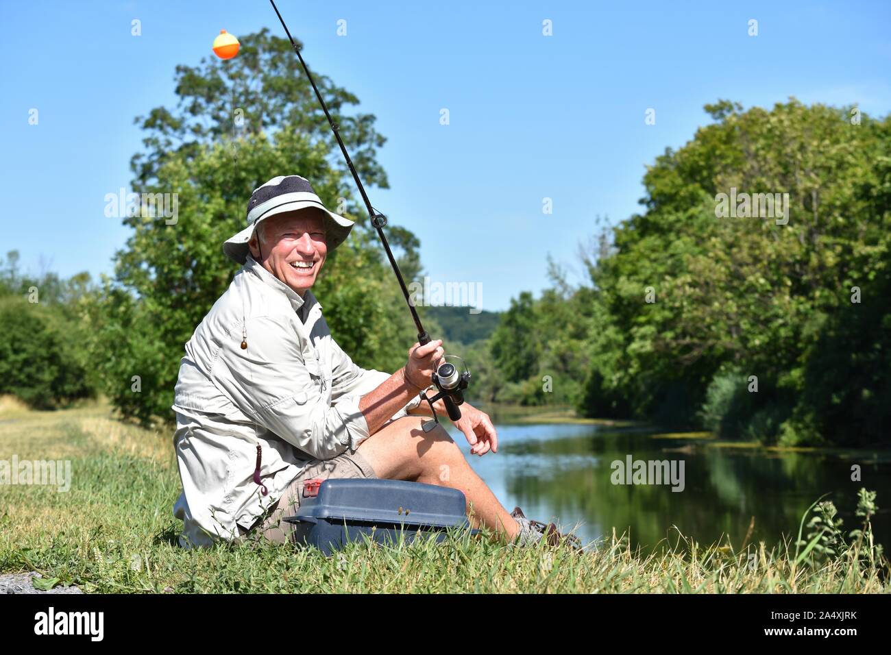 Smiling Retired Male Fisherman With Rod And Reel Outdoors Stock Photo