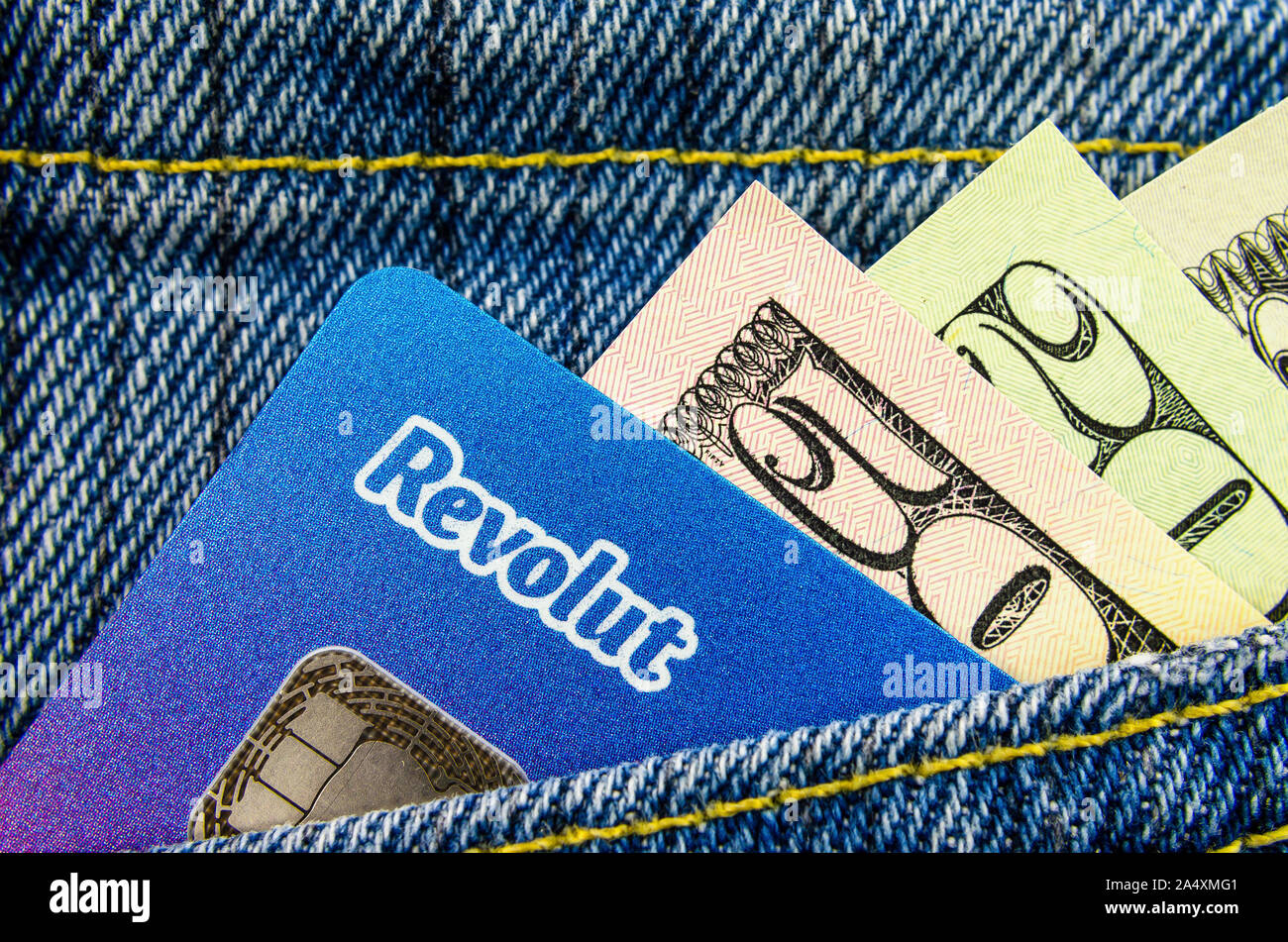 Revolut bank card with the dollar bills sticking out of the jeans pocket. Macro photo. Stock Photo