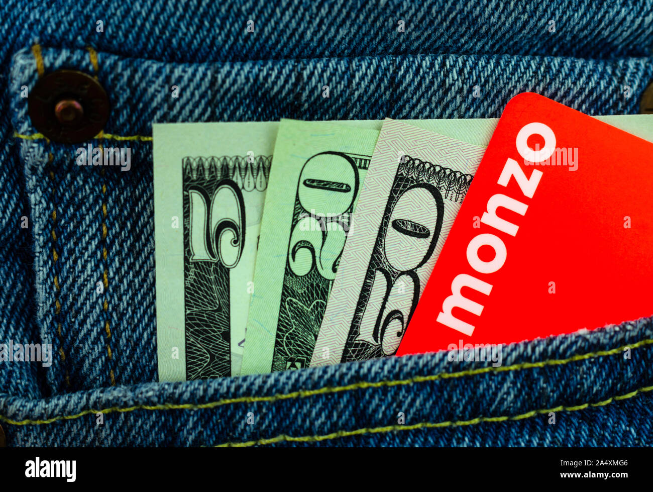 Monzo bank card and dollar bills in the jeans pocket. Macro photo. Stock Photo