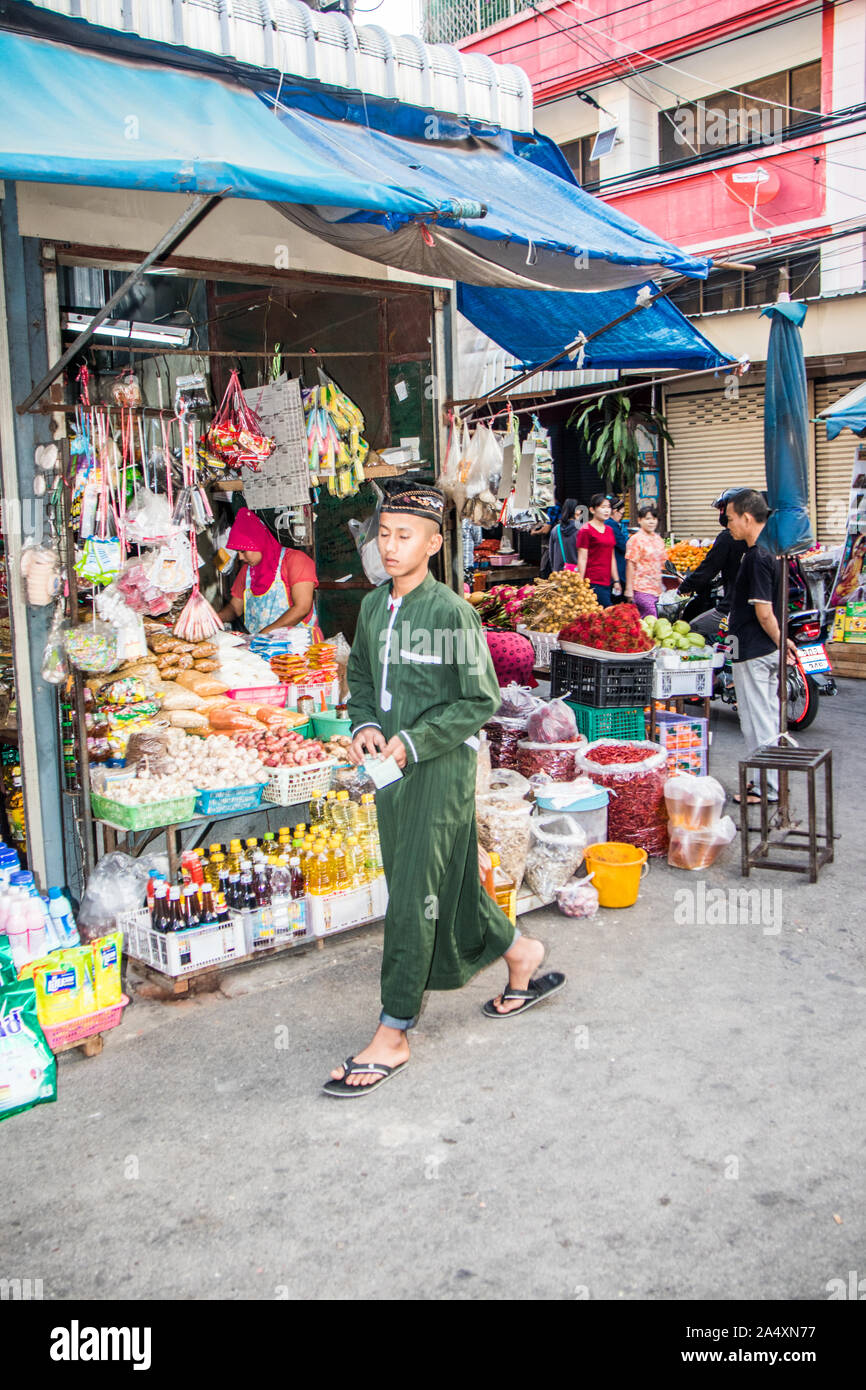 Mae Sot, Thailand - February 3rd 2019: A young muslim man walks past a grocery shop on the market. The market is a daily occurrence. Stock Photo