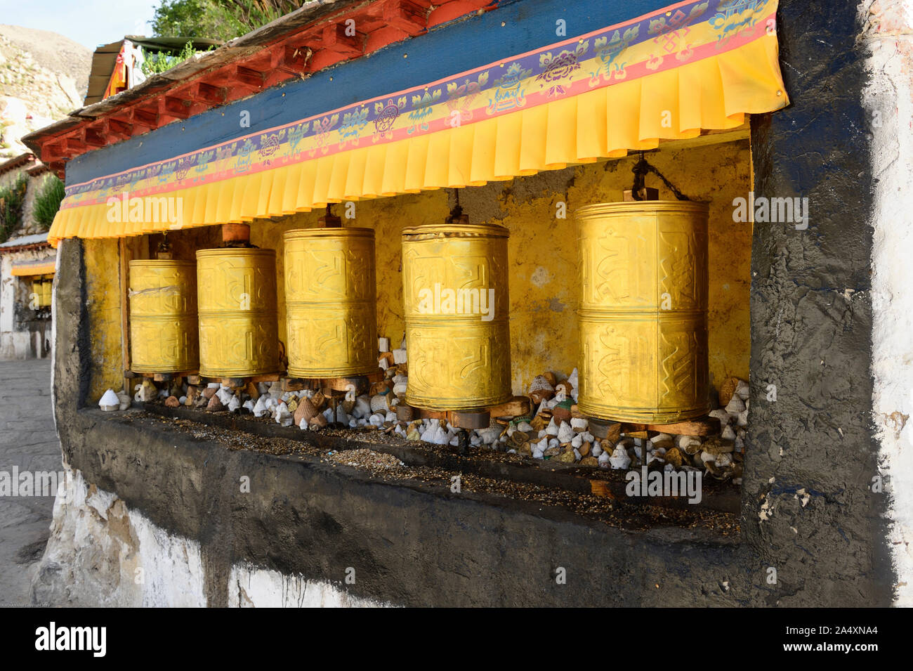 Golden prayer wheels at Drepung Monastery wait for  a worshipper of Tibetan Bhuddhism to spin a prayer out to the Universe. Stock Photo