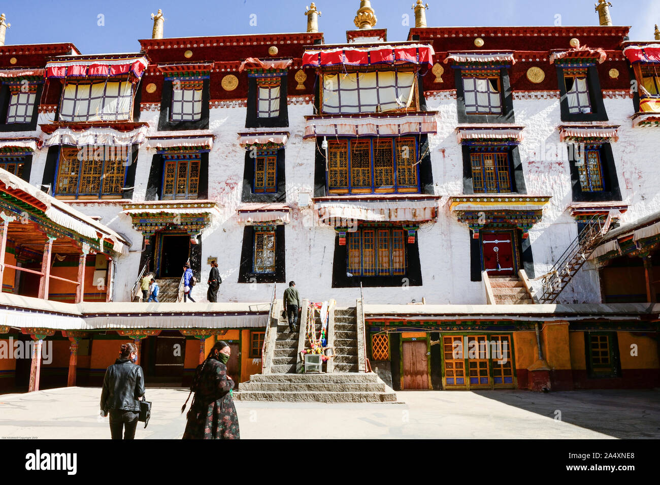 Tibetan Bhuddist mountain people cross the courtyard to climb stairs leading in to Drepung Monastery in Lhasa, Tibet. Stock Photo