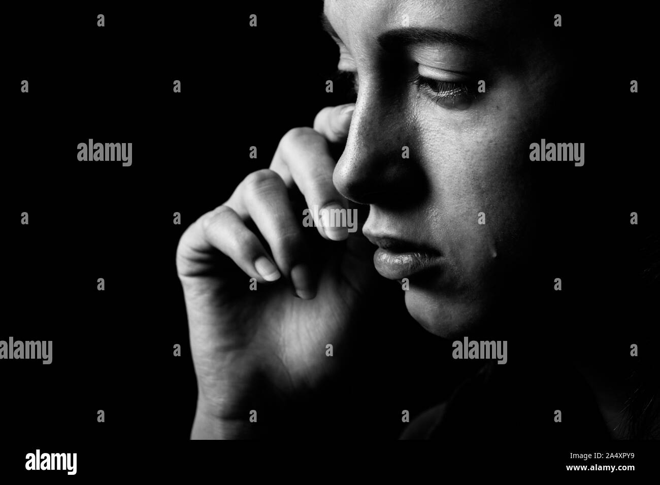 sad woman crying on black background, looking down, closeup portrait, monochrome Stock Photo
