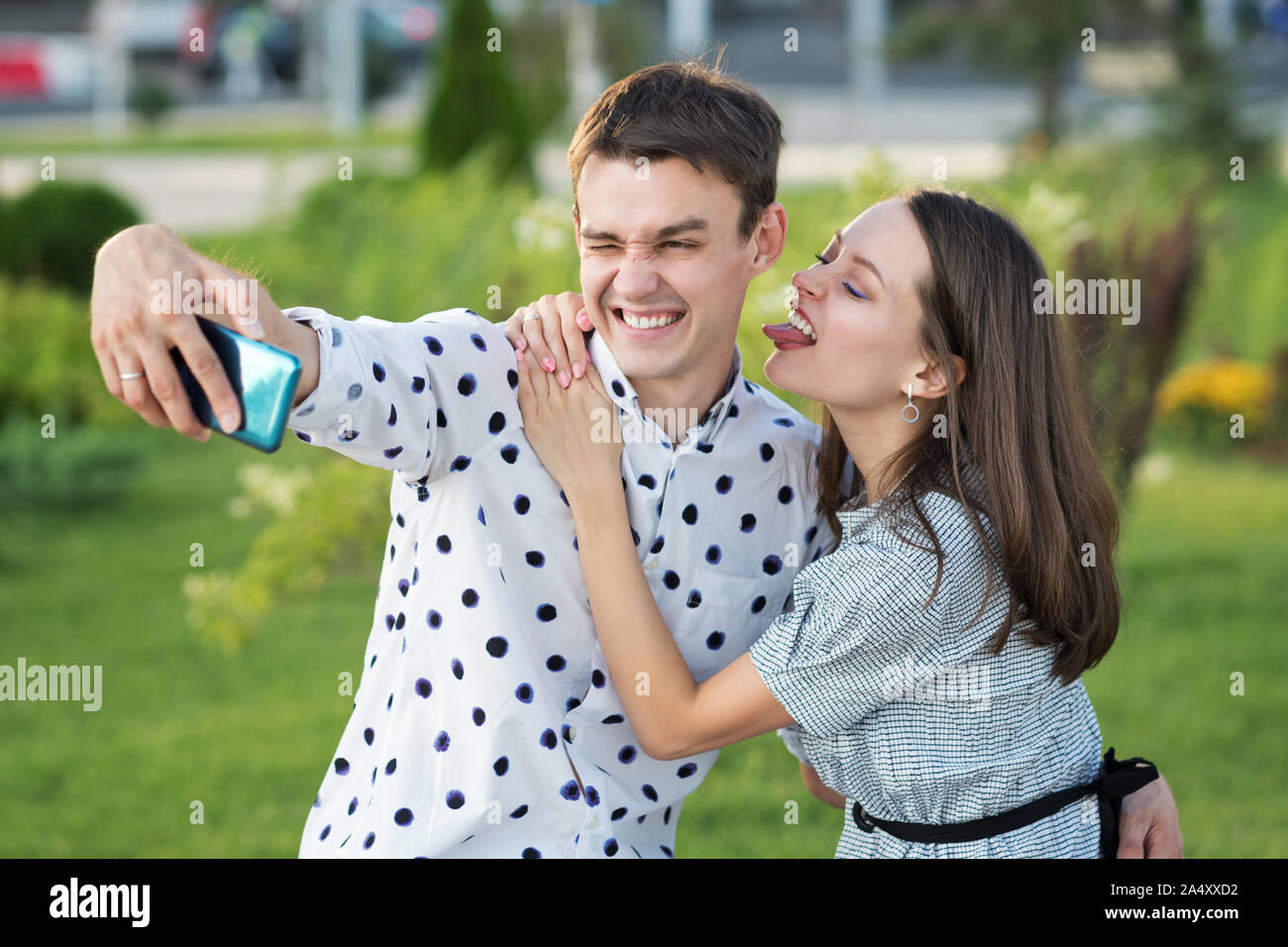 Beautiful couple in love dating outdoors and smiling. Girl persuades her boyfriend to take a picture of herself together. Selfie. Keep a moment in min Stock Photo