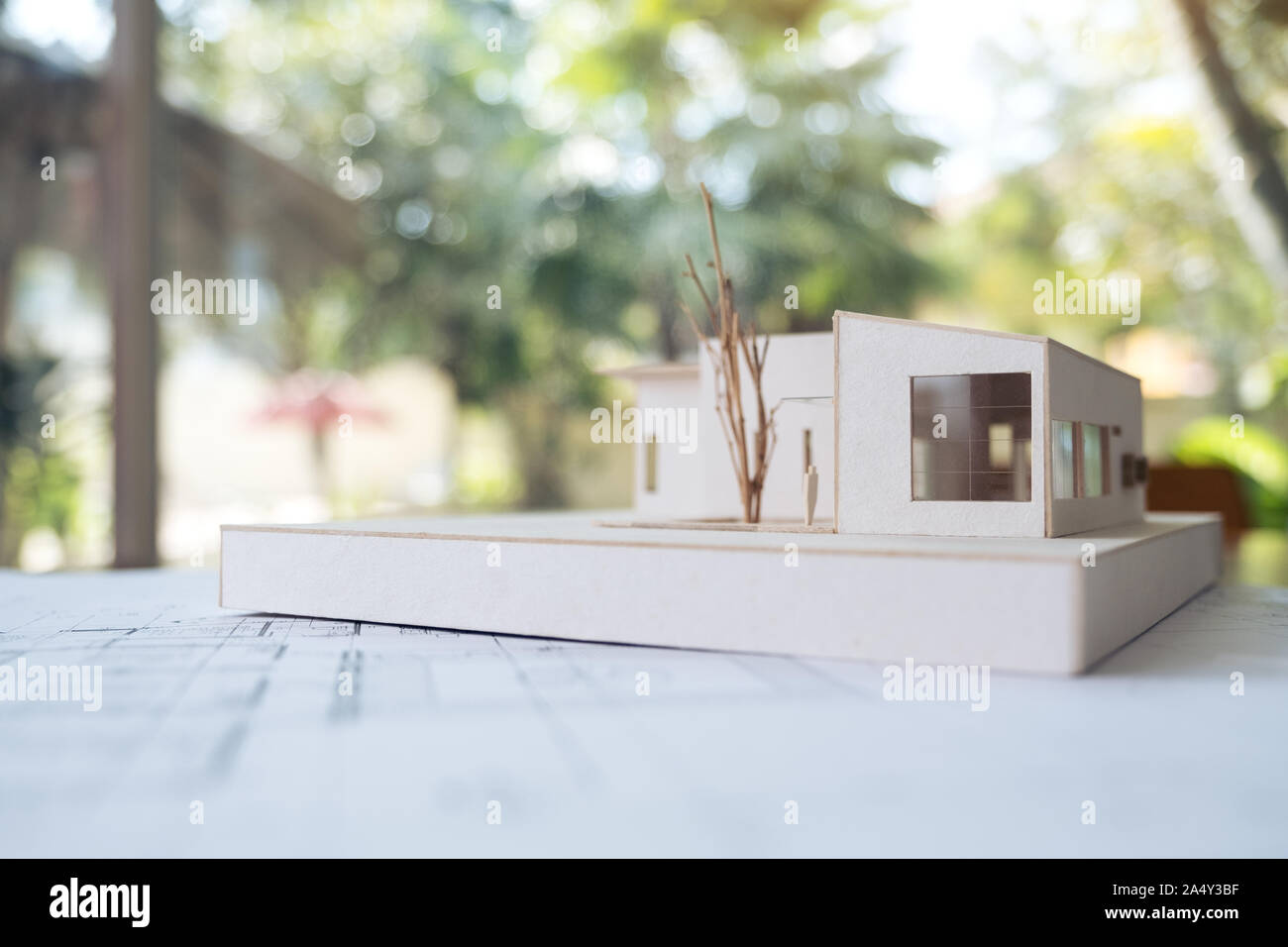 An architecture model with shop drawing paper and laptop on table in office with blur nature background Stock Photo