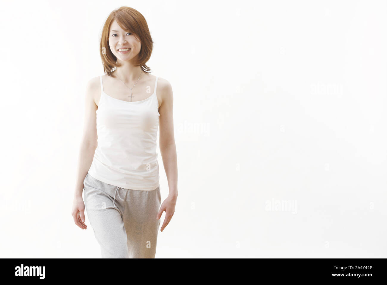 Beautiful young woman (model) poses in studio wearing white tank top Stock Photo