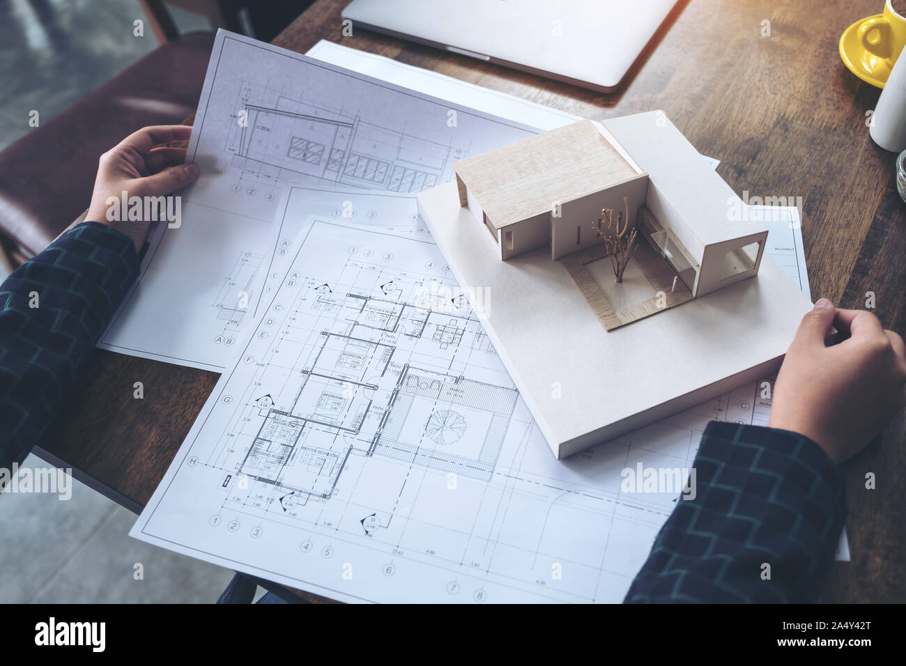 An architect working and looking at an architecture model with shop drawing paper on table Stock Photo