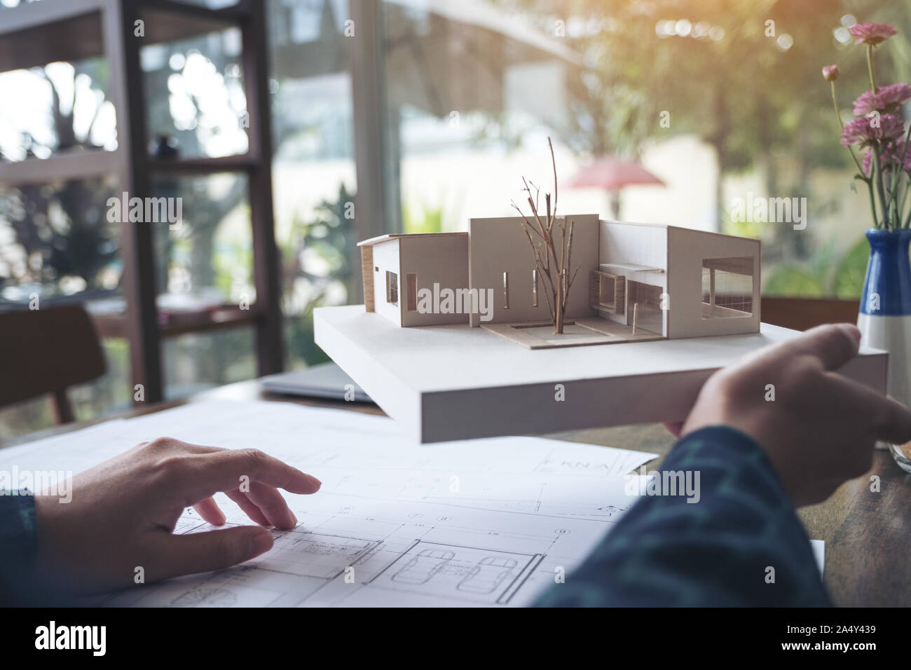 An architect working and holding an architecture model with shop drawing paper on table Stock Photo