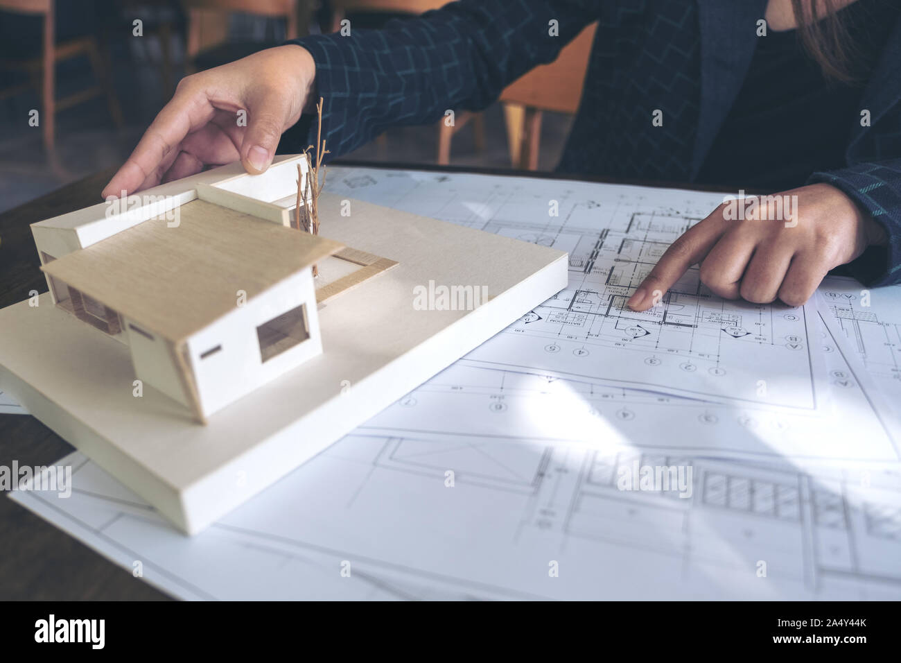 An architect working and pointing at architecture model with shop drawing paper on table Stock Photo