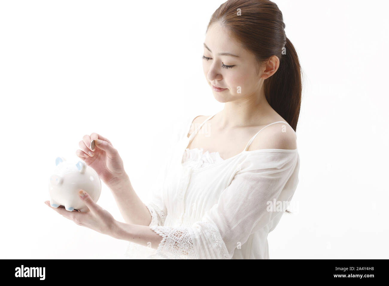 Woman putting coins into piggy bank Stock Photo - Alamy