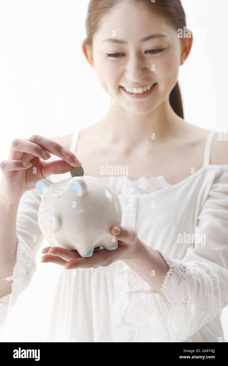 Woman putting coins into piggy bank Stock Photo - Alamy
