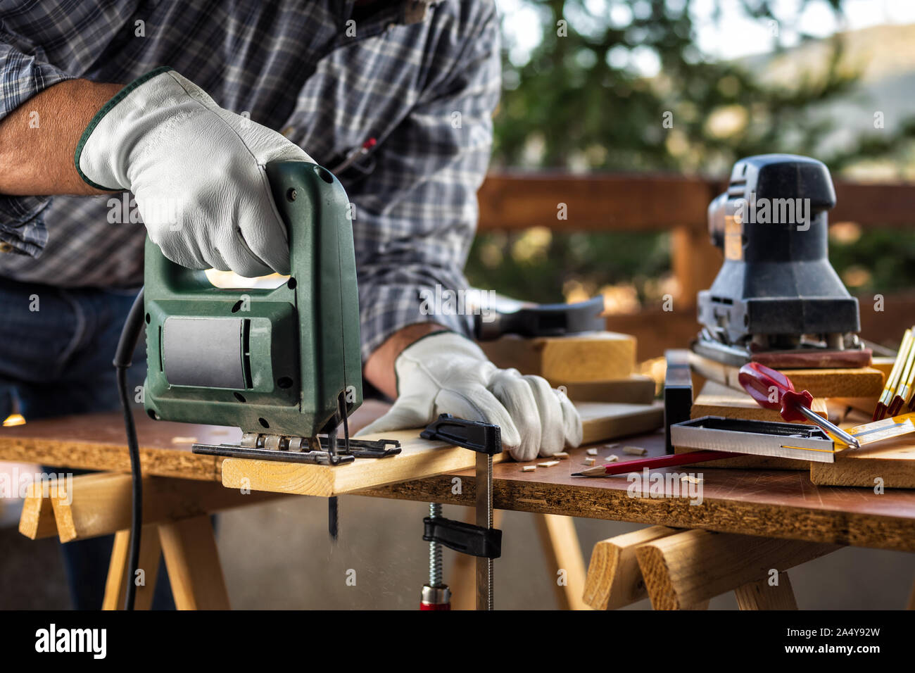 Adult carpenter craftsman wears protective leather gloves, with