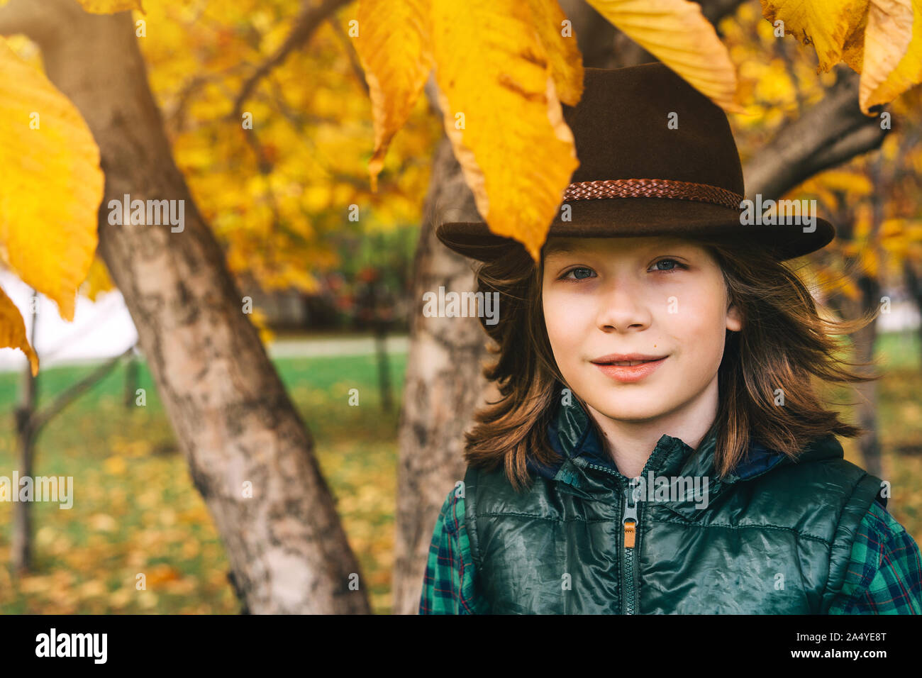 A cute 11 year old boy with long brown hair in a cowboy felt hat Stock