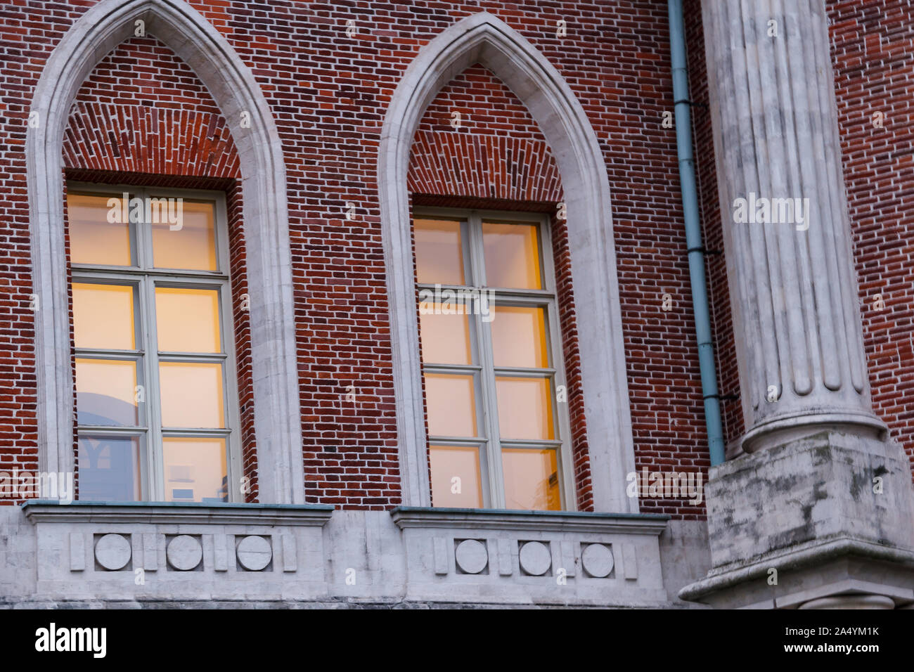 The windows of the old red brick castle built in the Gothic style have ...