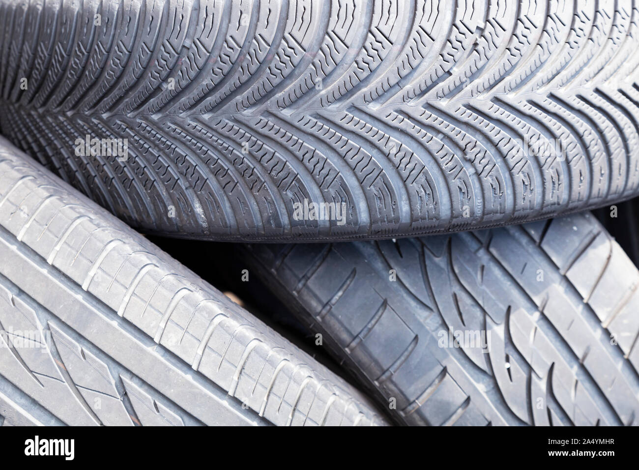 Close-up of used and old car tires with worn down treads randomly piled up in a stack Stock Photo