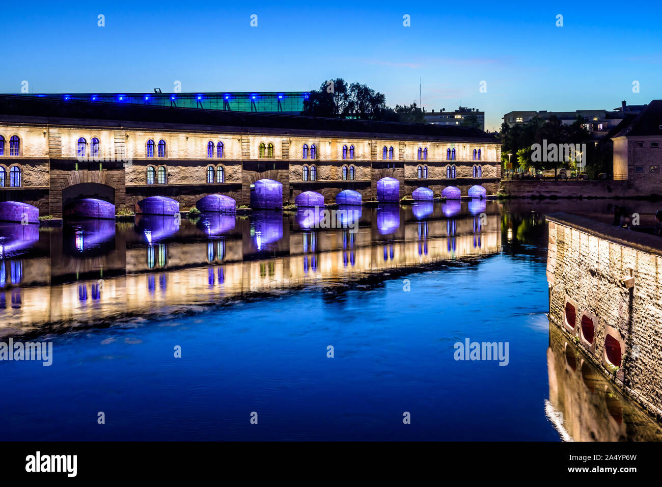 The Vauban Dam illuminated at nightfall in Strasbourg, France, a defensive work on the river Ill in the Petite France historic quarter. Stock Photo