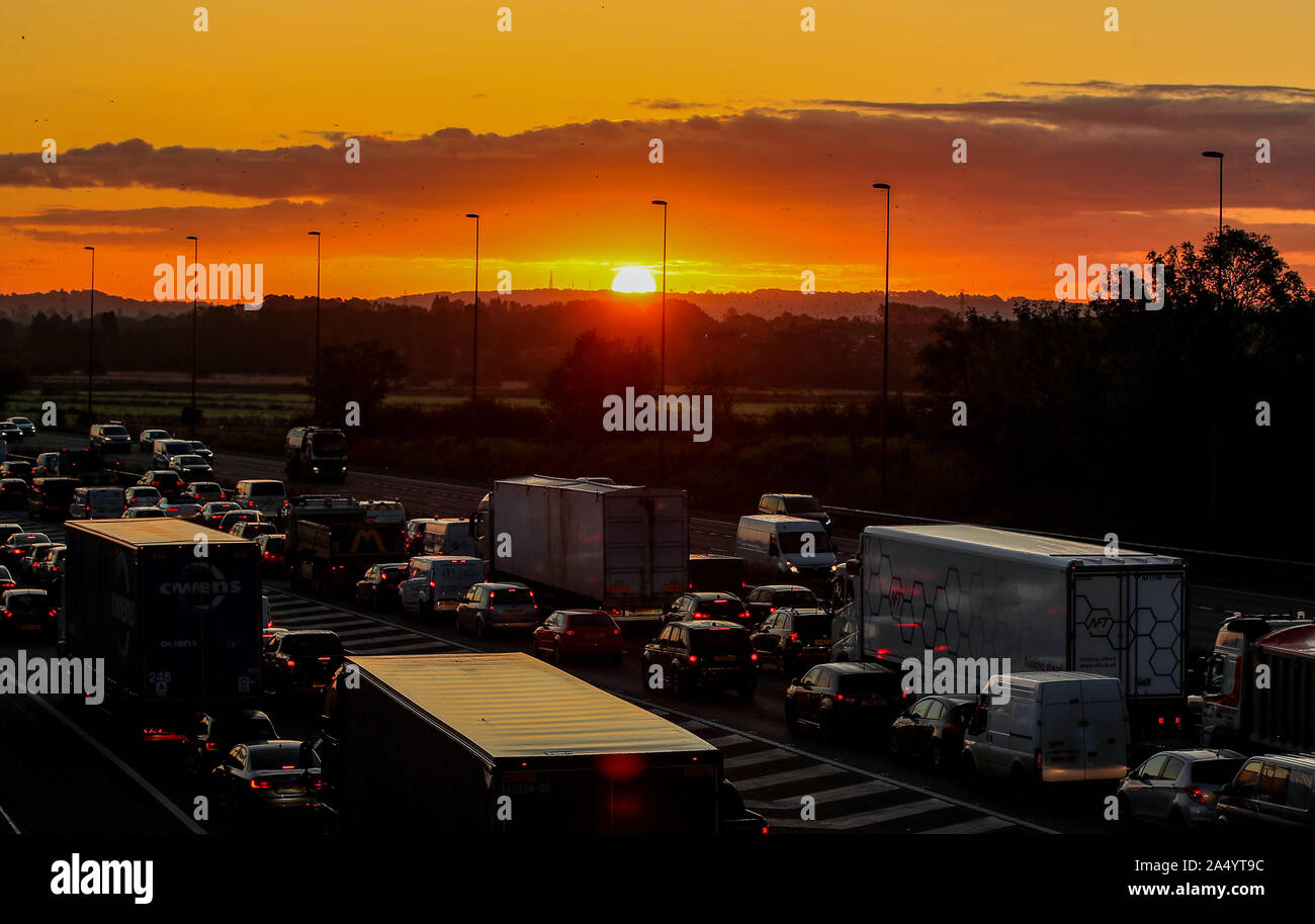 The sun rises behind the traffic on the M56 during the morning rush hour in Cheshire. Stock Photo