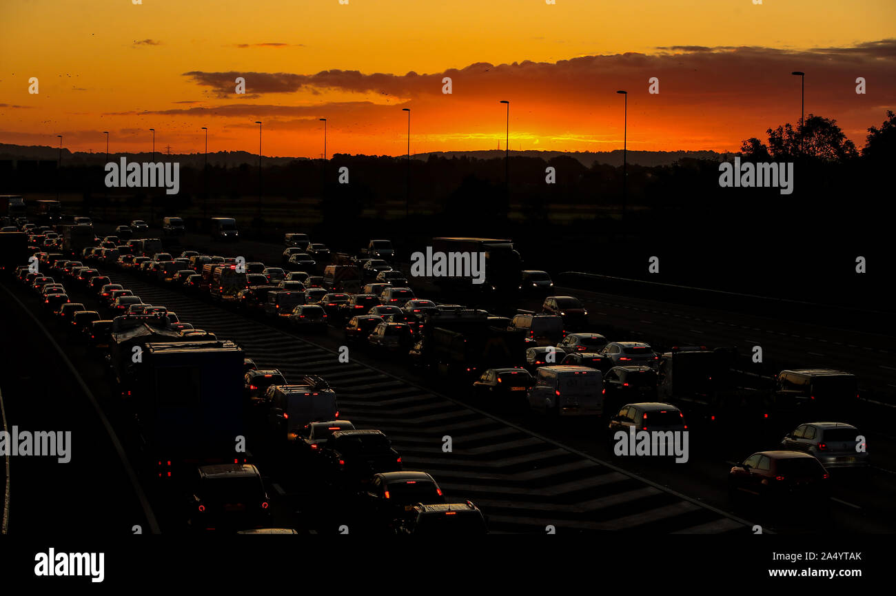 The sun rises behind the traffic on the M56 during the morning rush hour in Cheshire. Stock Photo