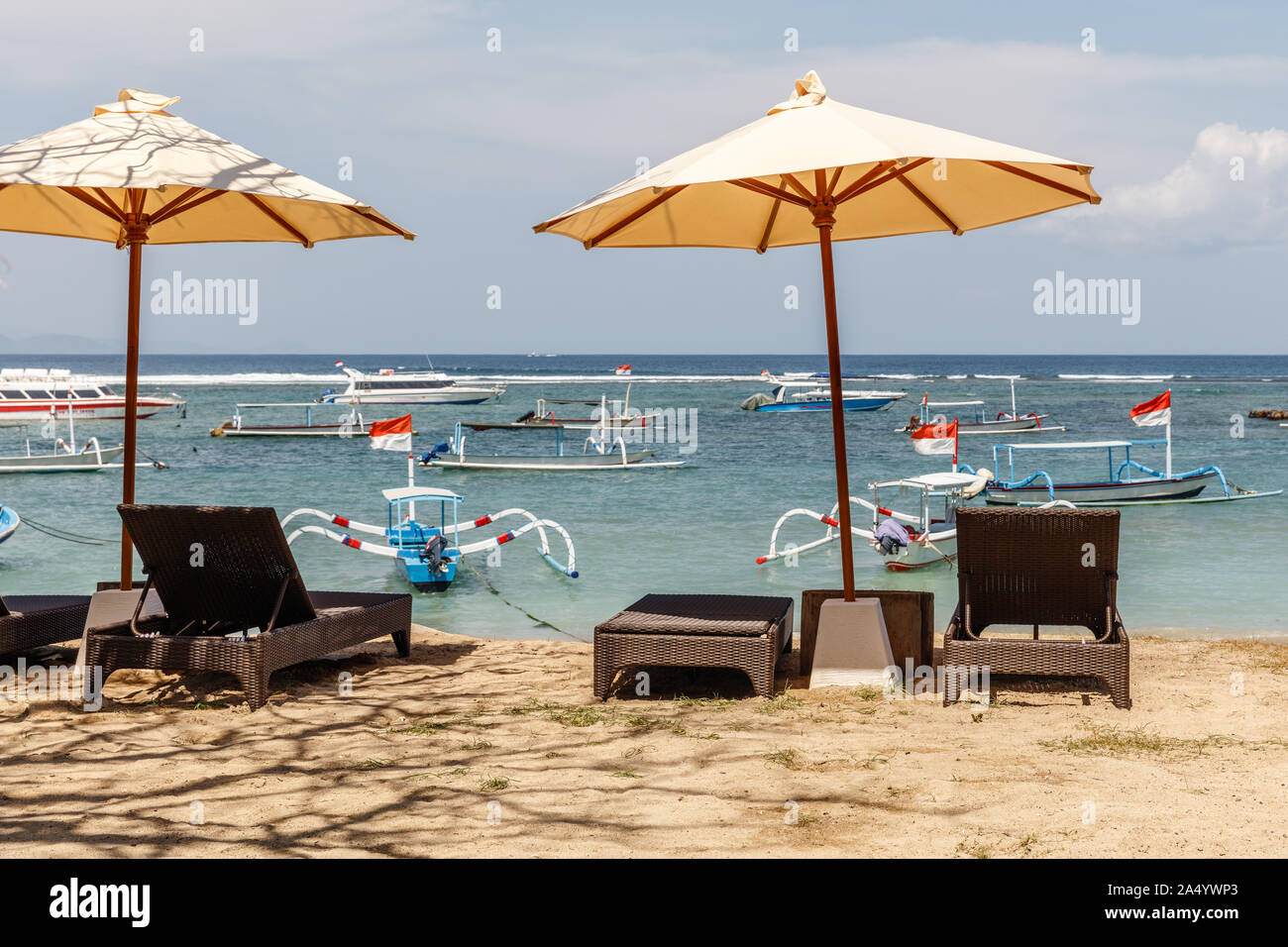Beach umbrellas at Sanur beach. Ocean, boats, blue sky. Bali, Indonesia